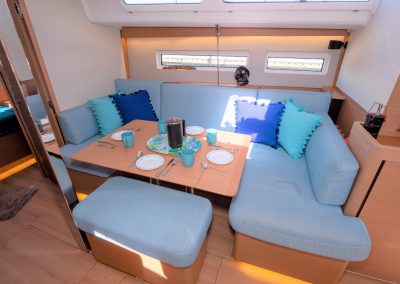 The interior of a boat with blue couches and a table.